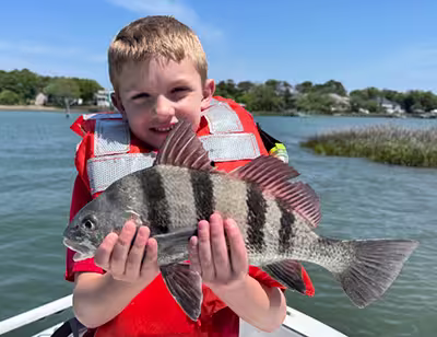 Kids fishing charter in Ocean Isle Beach, NC – Catching black drum with Salty Dawg Fishing Charters Young angler holding a black drum caught on a kids fishing charter in Ocean Isle Beach, NC