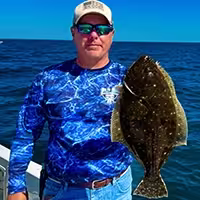 Captain Harvey Wall holding a reportable flounder in NC
