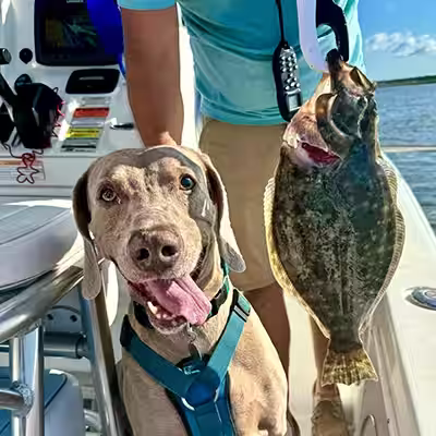 Oakley standing on the boat beside a flounder, happy and alert during a fishing trip