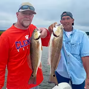 Two Anglers Holding redfish Caught from Ocean Isle Beach