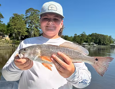 Redfish caught on a family-friendly kids fishing charter with Salty Dawg Fishing Charters – Ocean Isle Beach, NC Young kid holding a nice redfish caught on a kids fishing charter in Ocean Isle Beach, NC