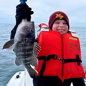 Young boy holding a keeper sea bass caught in Ocean Isle Beach in March